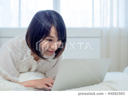 婦女在床上的操作一台計算機 44892985