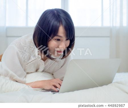 婦女在床上的操作一台計算機 44892987