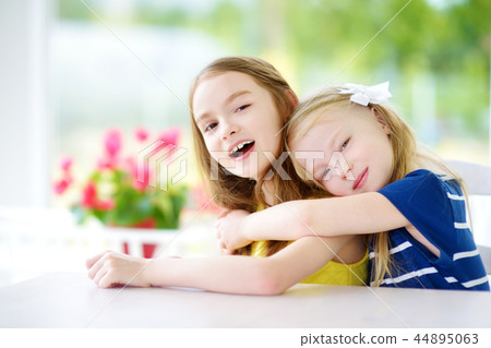Portrait of two cute little sisters at home on beautiful summer day Portrait of two cute little sisters at home on beautiful summer day 44895063