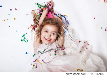 Holidays concept. Little funny girl lying in multicolored confetti on birthday party 44896902