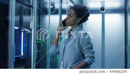 Black woman speaking on phone in server room Black woman speaking on phone in server room 44906284