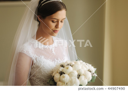 Young and tenderness bride in wedding dress hold bouquet. Happy bride in her wedding day Young and tenderness bride in wedding dress hold bouquet. Happy bride in her wedding day 44907490