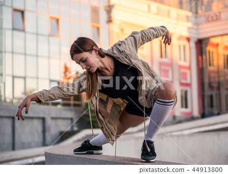 Outdoor lifestyle image of a young pretty chestnut haired caucasian girl posing and dancing on the 44913800