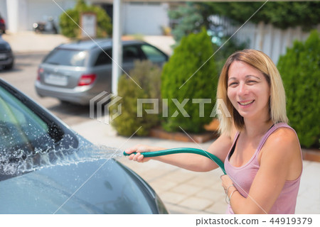 Young woman washing car with hose. Car detailing. 44919379