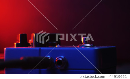 Extremely close up of button for effect electro guitar pedal. Red neon light in night club during Extremely close up of button for effect electro guitar pedal. Red neon light in night club during 44919631