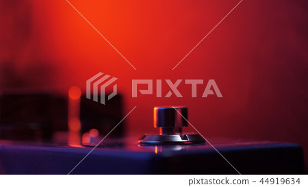 Extremely close up of button for effect electro guitar pedal. Red neon light in night club during Extremely close up of button for effect electro guitar pedal. Red neon light in night club during 44919634