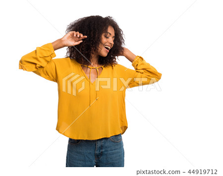 Beautiful black woman with afro hair in yellow autumn top having fun smiling and dancing in studio 44919712