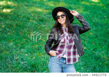 Portrait of happy mixed race young woman in hat. Hispanic hipster girl in the park. Lady wearing 44921778
