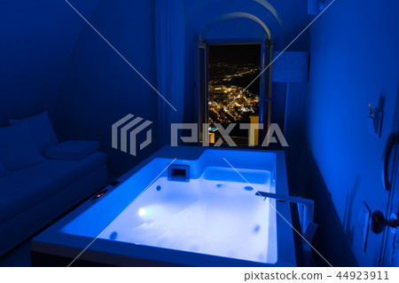 Luxury travel Santorini vacation hotel jacuzzi in colored lights with night view of the city. 44923911