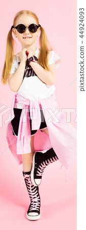 Girl with red tails on a pink background. A charming girl in bright sports clothes and sunglasses Girl with red tails on a pink background. A charming girl in bright sports clothes and sunglasses 44924093