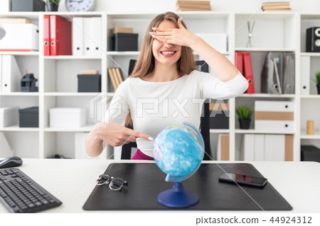 A young girl sitting in the office and in front of her on the table is a globe. A young girl sitting in the office and in front of her on the table is a globe. 44924312