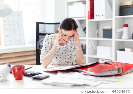 A young girl sitting in the office at the computer Desk, working with documents and holding hands on A young girl sitting in the office at the computer Desk, working with documents and holding hands on 44924975