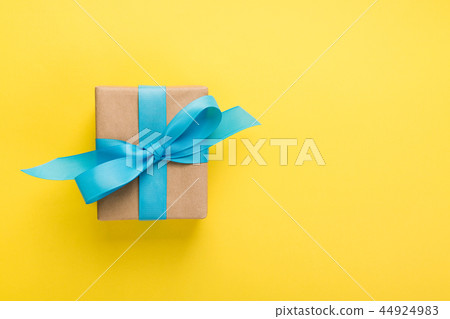 gift wrapped and decorated with blue bow on yellow 44924983