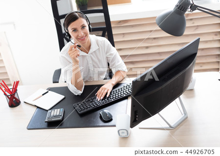 A young girl in headphones with a microphone sitting at a computer table. A young girl in headphones with a microphone sitting at a computer table. 44926705