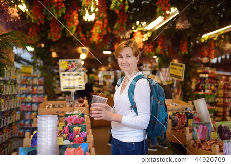 The famous Amsterdam flower market (Bloemenmarkt). Mature women choose tulip bulbs. The famous Amsterdam flower market (Bloemenmarkt). Mature women choose tulip bulbs. 44926709