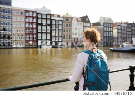 Mature woman looking at the famous dancing houses of Amsterdam on sunny day Mature woman looking at the famous dancing houses of Amsterdam on sunny day 44926710