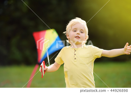 Little boy on a sunny day launches a flying kite. 44926898