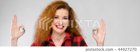 Portrait of beautiful redhead happy young woman smiling showing ok sign on gray background Portrait of beautiful redhead happy young woman smiling showing ok sign on gray background 44927270
