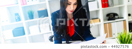 Beautiful young girl working with calculator and documents in the office at the table Beautiful young girl working with calculator and documents in the office at the table 44927576