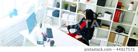 Beautiful young girl fills the documents, sitting in the office at the table. Beautiful young girl fills the documents, sitting in the office at the table. 44927578