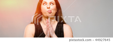Emotional smiling happy plus size model standing in studio looking in camera talking on phone with 44927645