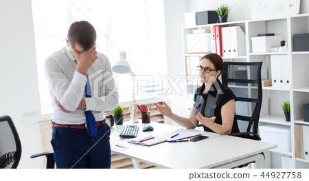 A young girl sitting in the office at the computer table. Next to her is a young man. 44927758