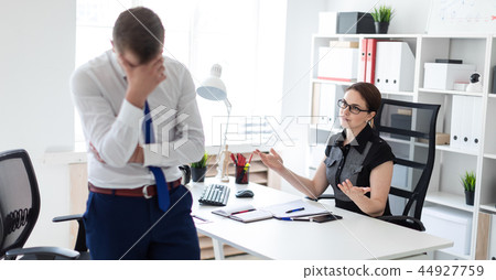A young girl sitting in the office at the computer table. Next to her is a young man. 44927759
