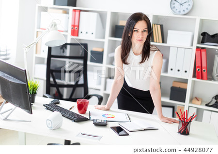 A young girl standing in the office near the computer Desk. 44928077
