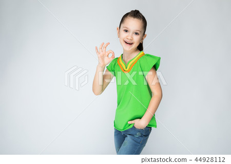 Girl on a gray background shows the sign OK. 44928112