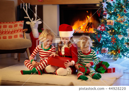Child at Christmas tree. Kids at fireplace on Xmas 44928220