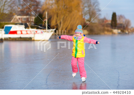Child ice skating on frozen mill canal in Holland. Child ice skating on frozen mill canal in Holland. 44928410
