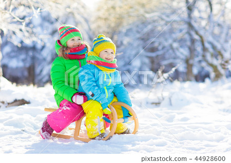 Kids play in snow. Winter sled ride for children Kids play in snow. Winter sled ride for children 44928600