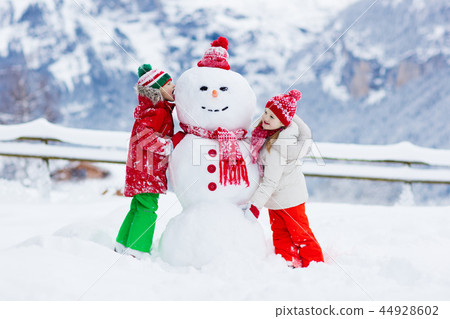 Child building snowman. Kids build snow man. 44928602