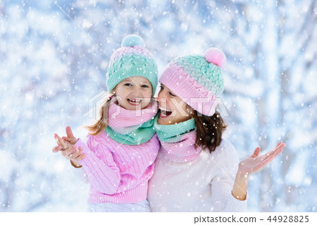 Mother and child in knitted winter hats in snow. Mother and child in knitted winter hats in snow. 44928825