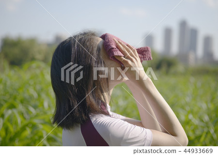 Woman wiping sweat middle jogging training outdoor active skyscraper green environment lifestyle 44933669