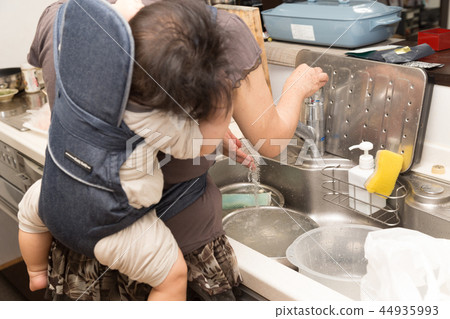 A senior doing housework while taking a baby (focus on senior) 44935993