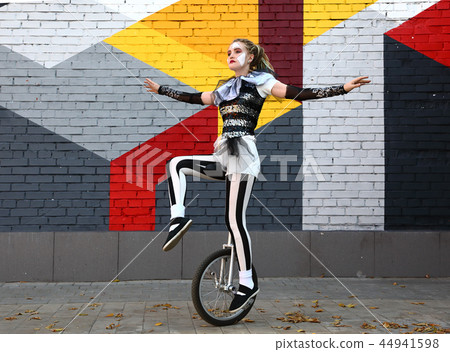 Girl clown rides a unicycle Girl clown rides a unicycle 44941598