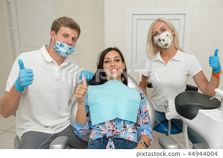 A dentist, his assistant and happy female patient 44944004