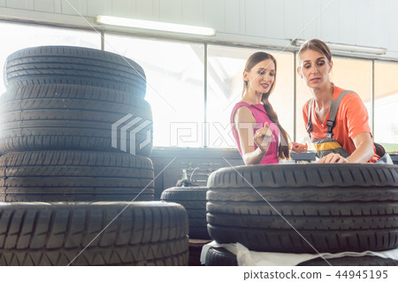 Helpful female auto mechanic checking the identification number of a tire Helpful female auto mechanic checking the identification number of a tire 44945195