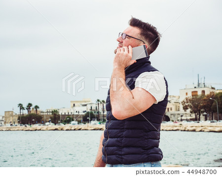 Stylish, happy man with a phone on the background of a sea 44948700