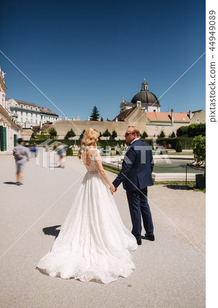 Beautiful young bride with her handsome groom walking in palace Belvedere 44949089