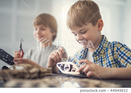 Calm boy kindly looking at his metal constructor and smiling Calm boy kindly looking at his metal constructor and smiling 44949832