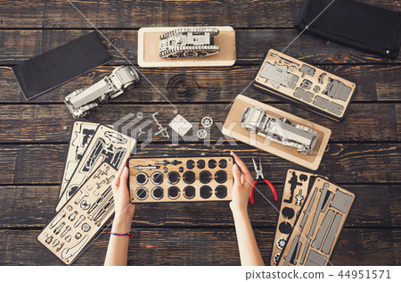 Top view of female hands holding parts of the constructor 44951571
