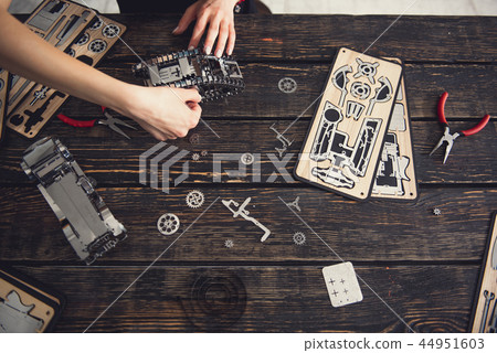 Top view of female hands constructing metal mechanism 44951603