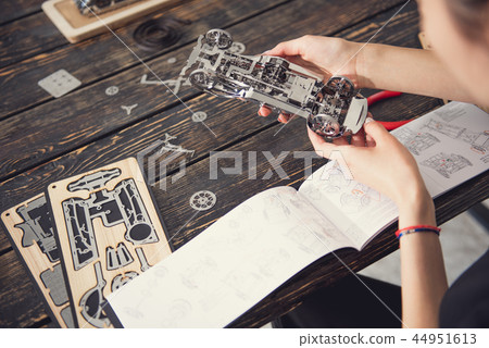 Attentive lady checking the instruction while making her constructor Attentive lady checking the instruction while making her constructor 44951613