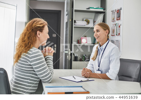 Young doctor is consulting joyful red-haired woman Young doctor is consulting joyful red-haired woman 44951639