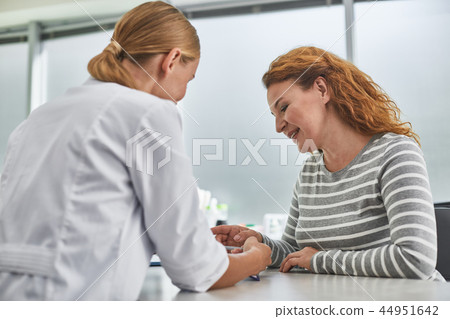 Beautiful middle-aged lady looking at clipboard in doctor hands and smiling Beautiful middle-aged lady looking at clipboard in doctor hands and smiling 44951642