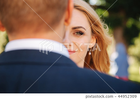 Brides half of the face is hidden behind the back of the groom Brides half of the face is hidden behind the back of the groom 44952309