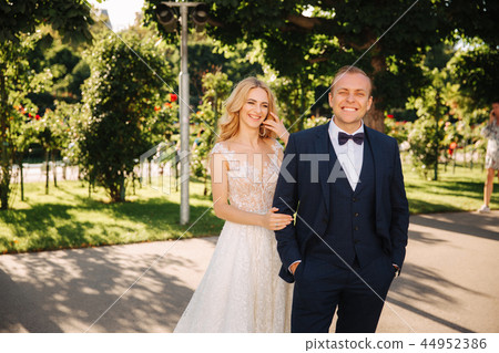 Happy young couple in their wedding day spend time in park. Green background Happy young couple in their wedding day spend time in park. Green background 44952386