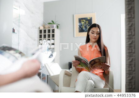 Calm woman is relaxing with magazine in salon Calm woman is relaxing with magazine in salon 44953376